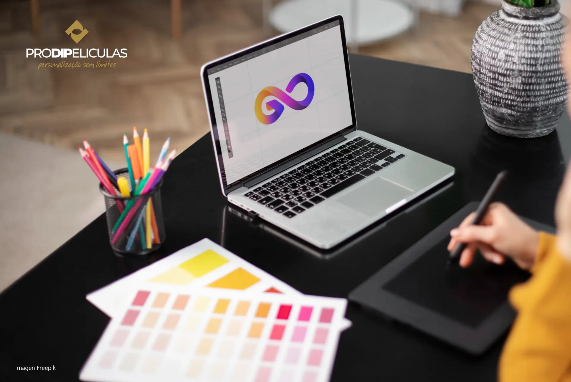 Pessoa projetando em um laptop e paleta de cores na mesa